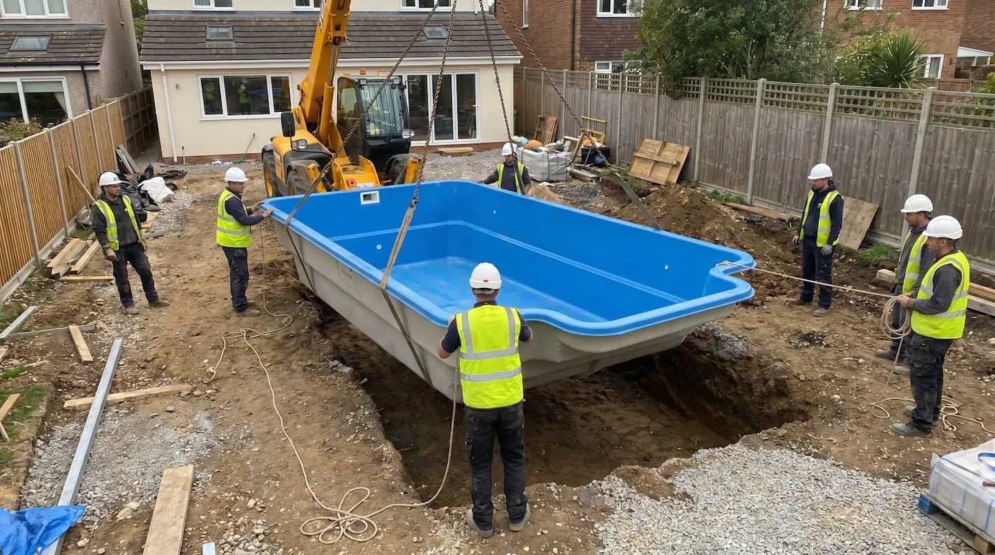Chantier d'installation d'une piscine enterrée avec coque polyester posée dans le sol creusé, entourée de machinerie de terrassement